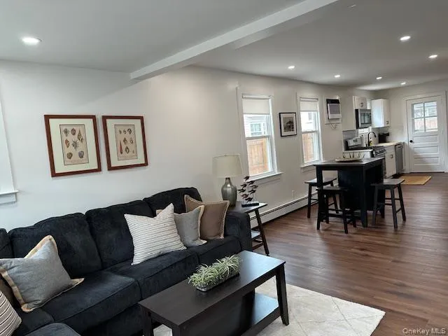 Living room with recessed lighting, a baseboard heating unit, dark wood-style flooring, plenty of natural light, and a wall unit AC Living room with recessed lighting, a baseboard heating unit, dark wood-style flooring, plenty of natural light, and a wall unit AC