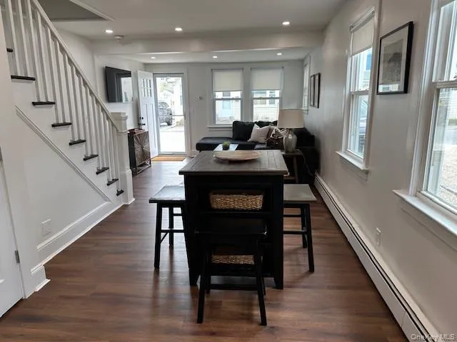 Dining room featuring a baseboard heating unit, dark wood finished floors, stairs, and recessed lighting Dining room featuring a baseboard heating unit, dark wood finished floors, stairs, and recessed lighting