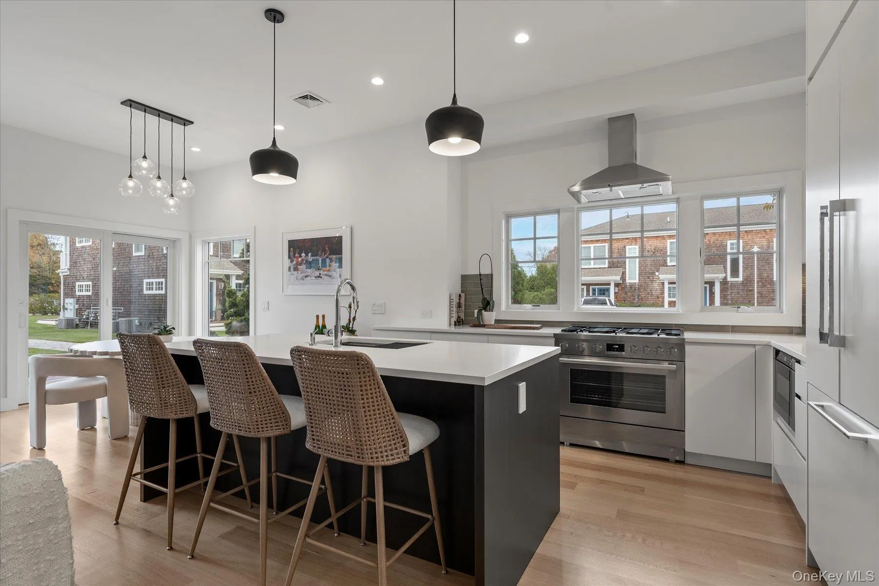 Kitchen featuring hanging light fixtures, appliances with stainless steel finishes, a breakfast bar, an island with sink, and extractor fan Kitchen featuring hanging light fixtures, appliances with stainless steel finishes, a breakfast bar, an island with sink, and extractor fan