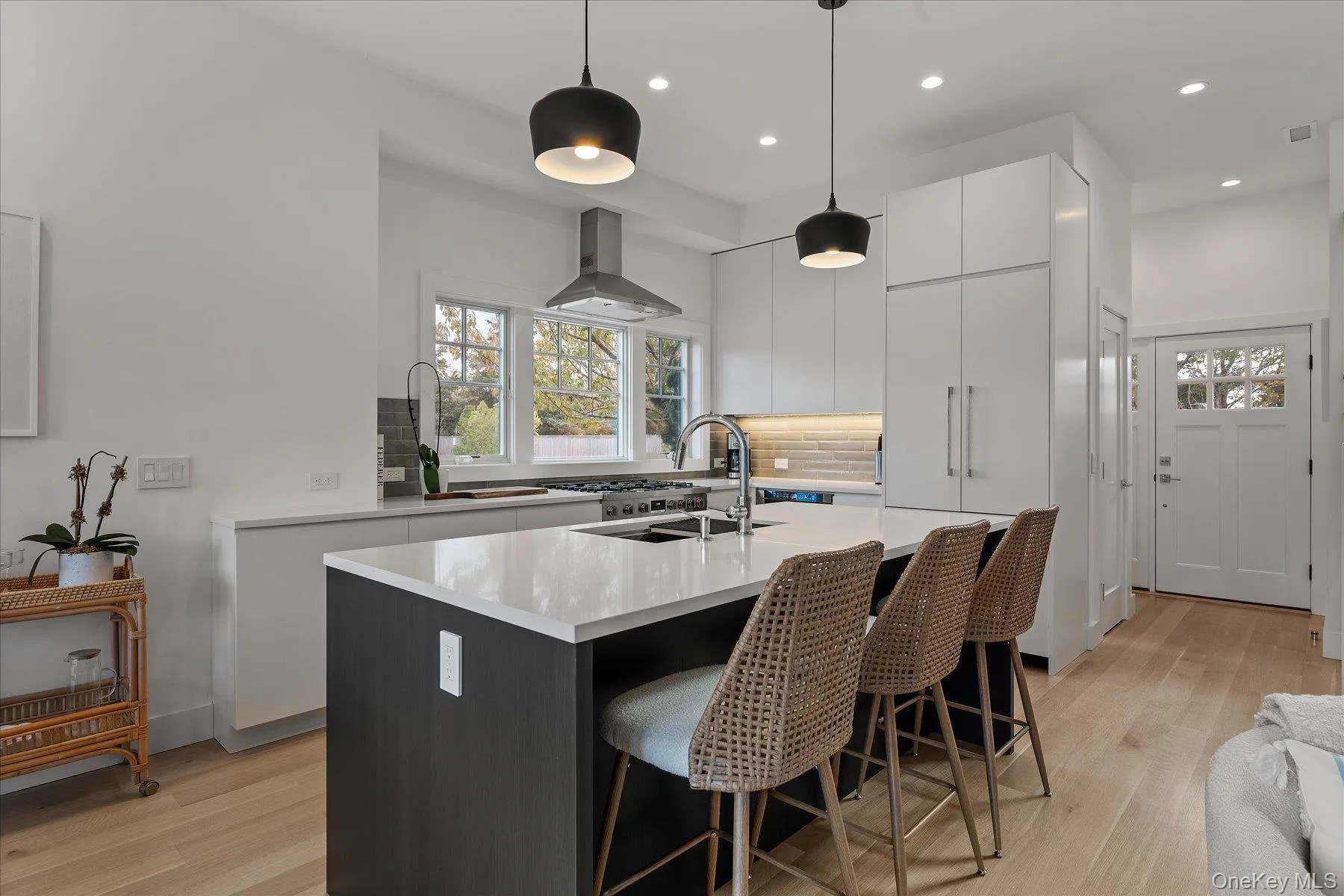 Kitchen with a kitchen bar, a kitchen island with sink, pendant lighting, modern cabinets, and light wood-type flooring Kitchen with a kitchen bar, a kitchen island with sink, pendant lighting, modern cabinets, and light wood-type flooring
