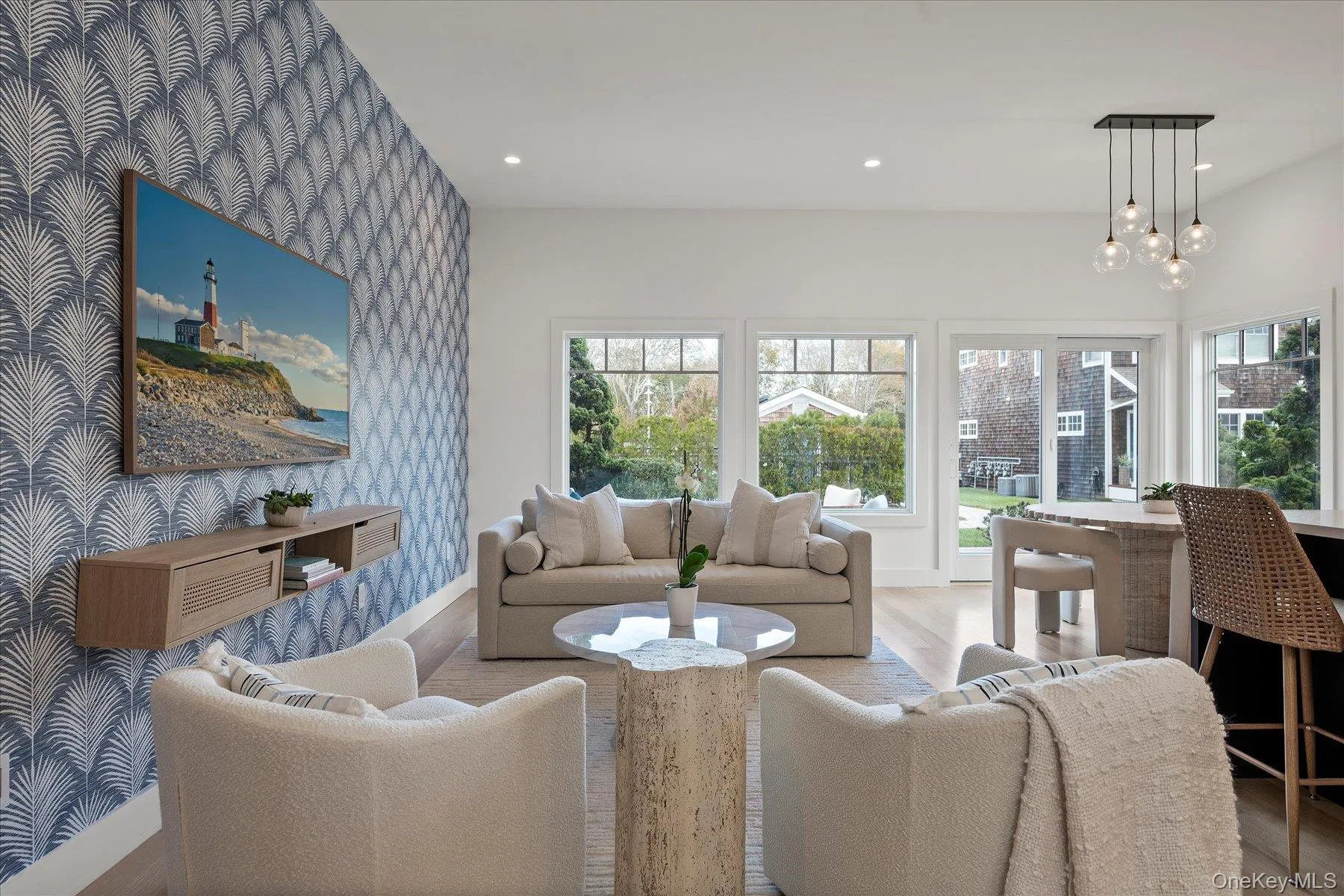 Living room with wallpapered walls, recessed lighting, an accent wall, wood finished floors, and a chandelier Living room with wallpapered walls, recessed lighting, an accent wall, wood finished floors, and a chandelier