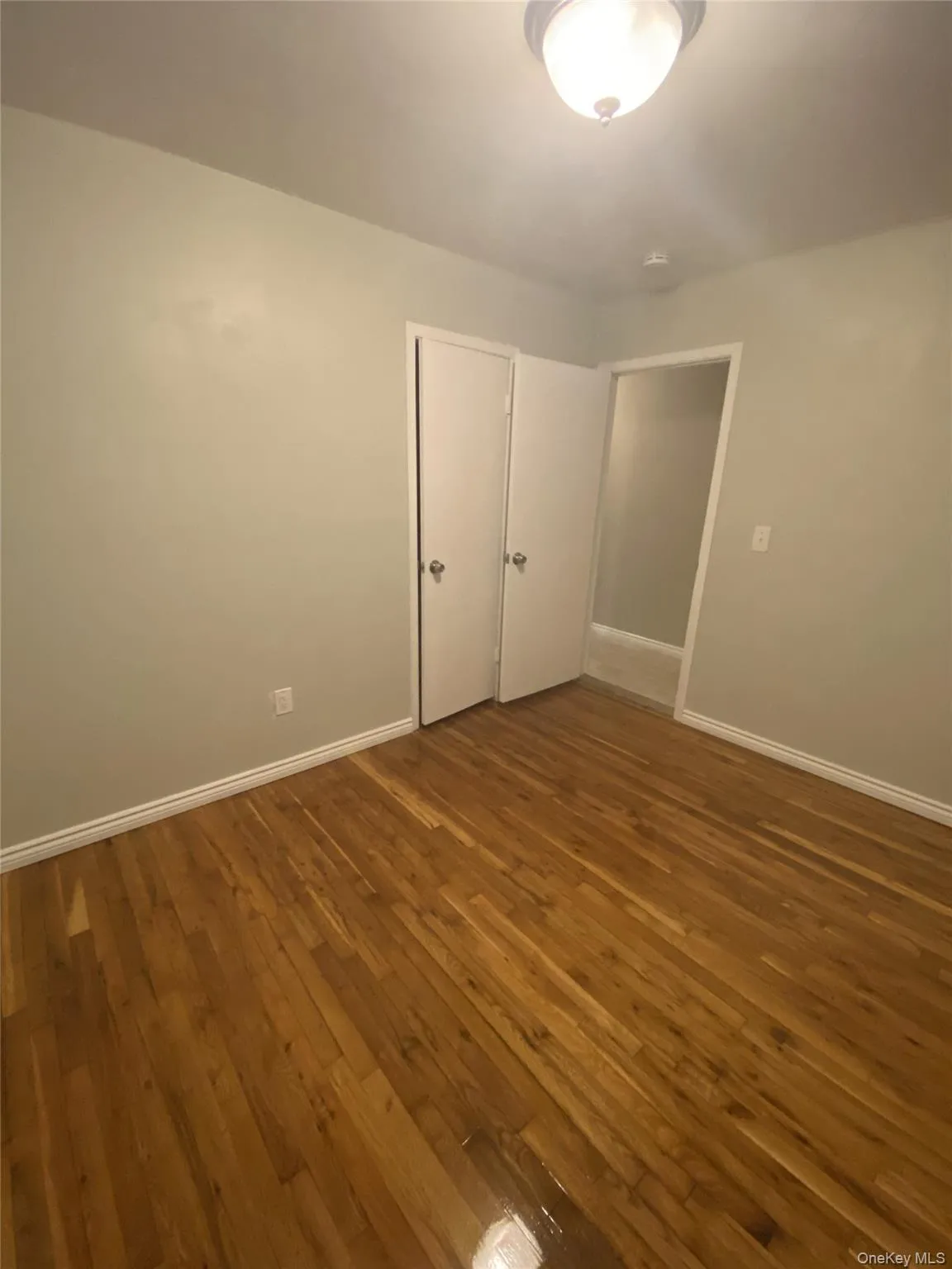 Spare room with dark wood-type flooring and baseboards Spare room with dark wood-type flooring and baseboards