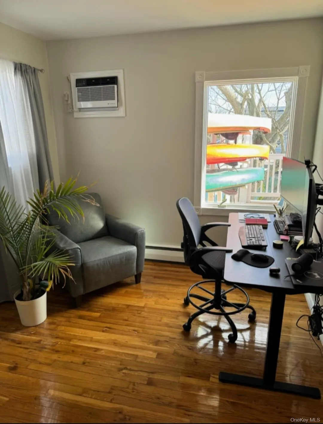 Home office with wood-type flooring, healthy amount of natural light, and a wall mounted AC Home office with wood-type flooring, healthy amount of natural light, and a wall mounted AC