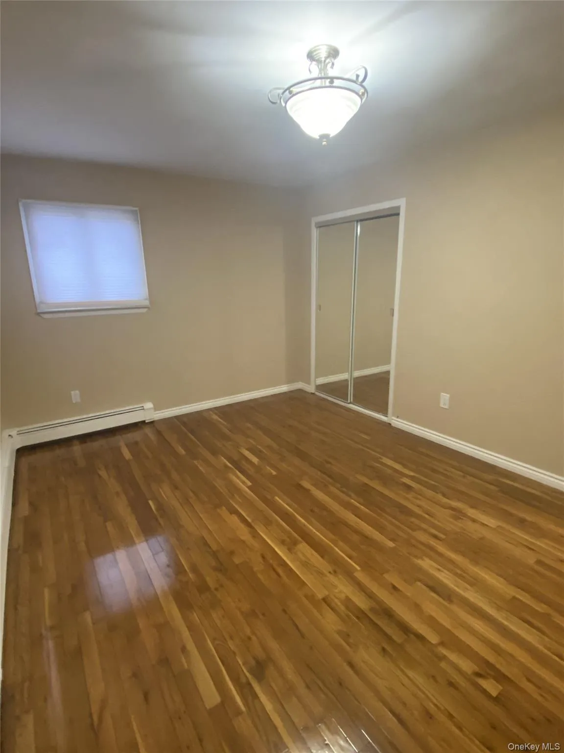 Spare room with dark wood-type flooring and baseboards Spare room with dark wood-type flooring and baseboards