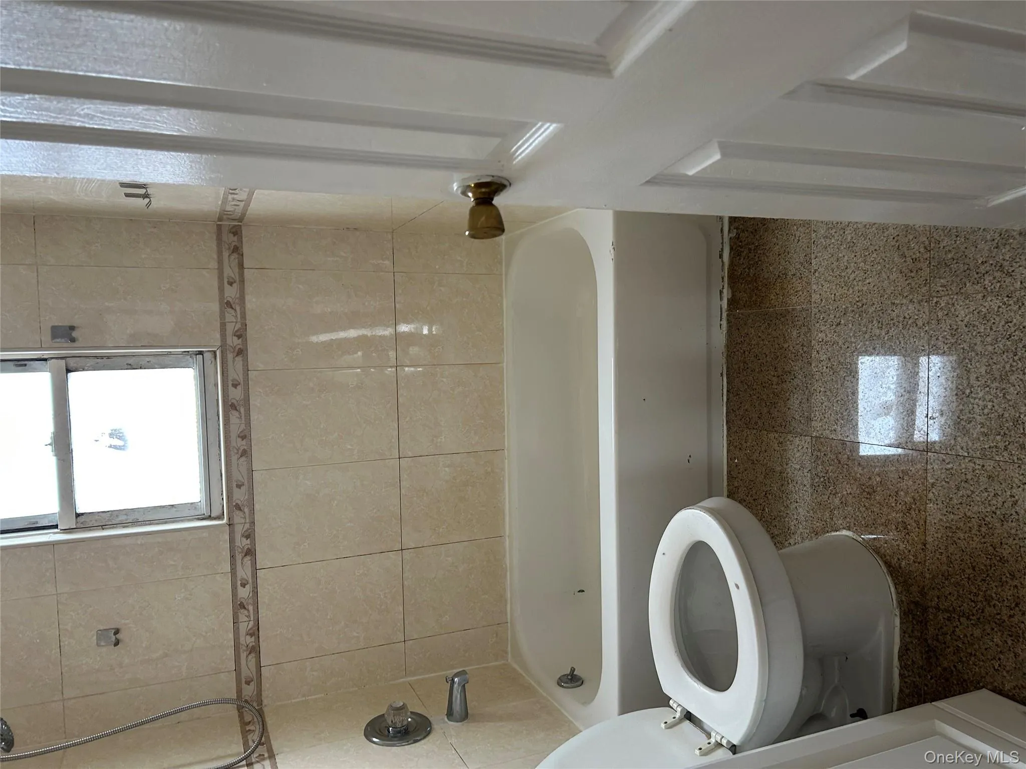 Full bathroom featuring granite tiled floors and bathing tub / shower combination Full bathroom featuring granite tiled floors and bathing tub / shower combination