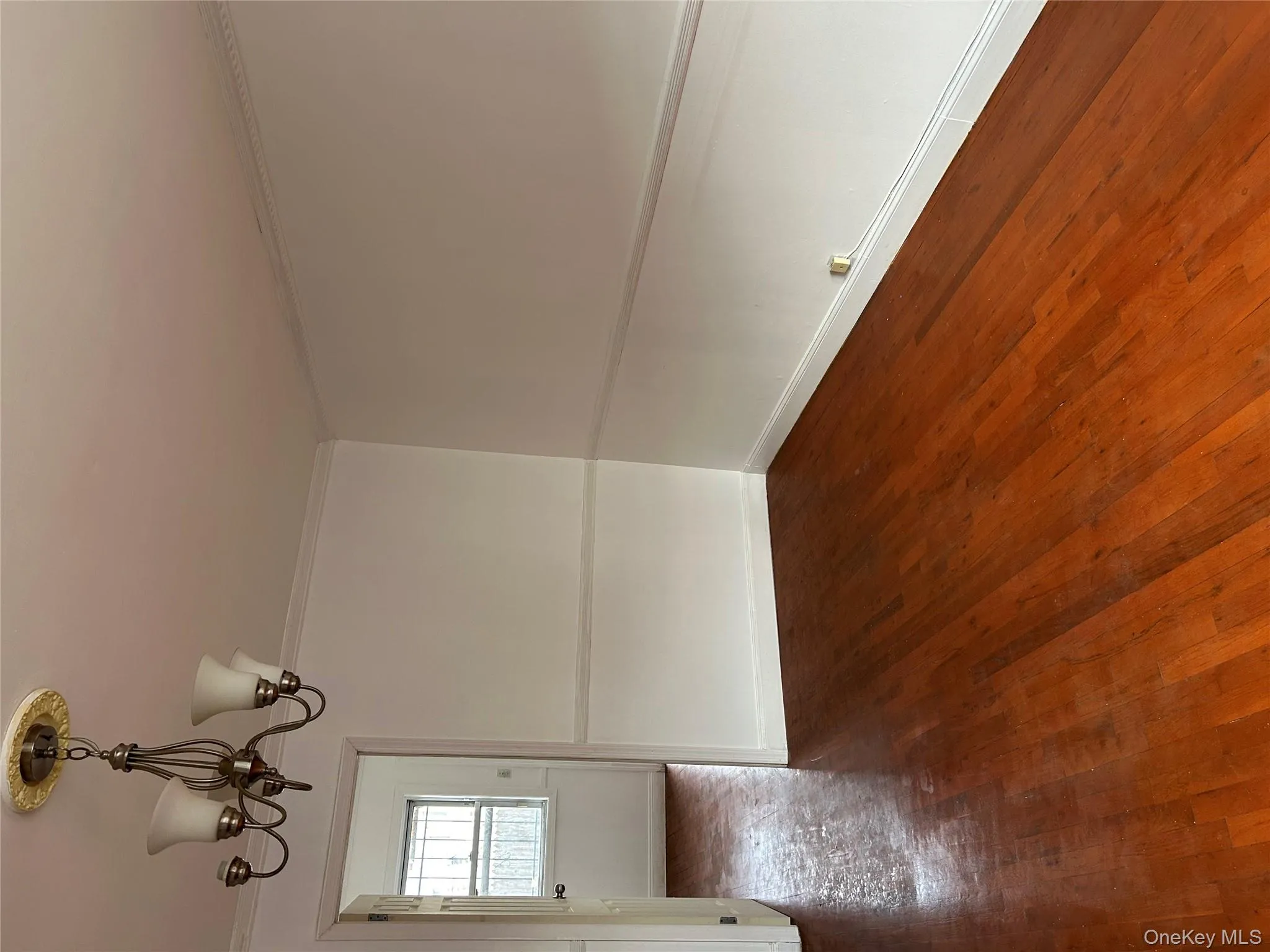 Spare room with a chandelier, dark wood-style floors, and crown molding Spare room with a chandelier, dark wood-style floors, and crown molding