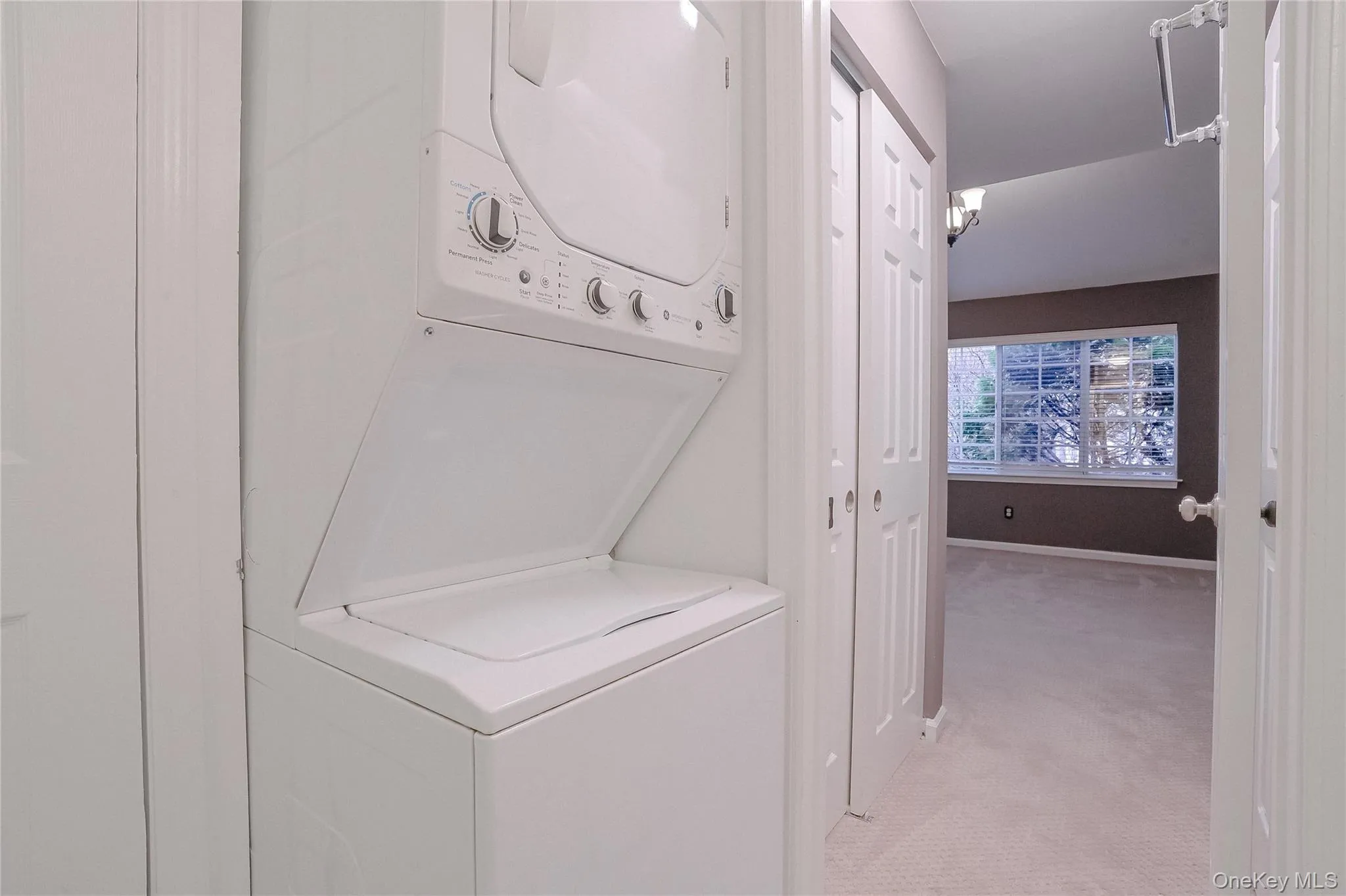 Laundry area with light colored carpet and stacked washer / drying machine Laundry area with light colored carpet and stacked washer / drying machine