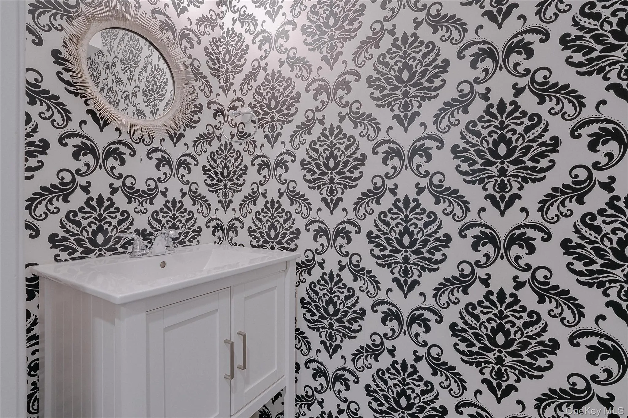 Bathroom with vanity and wallpapered walls Bathroom with vanity and wallpapered walls