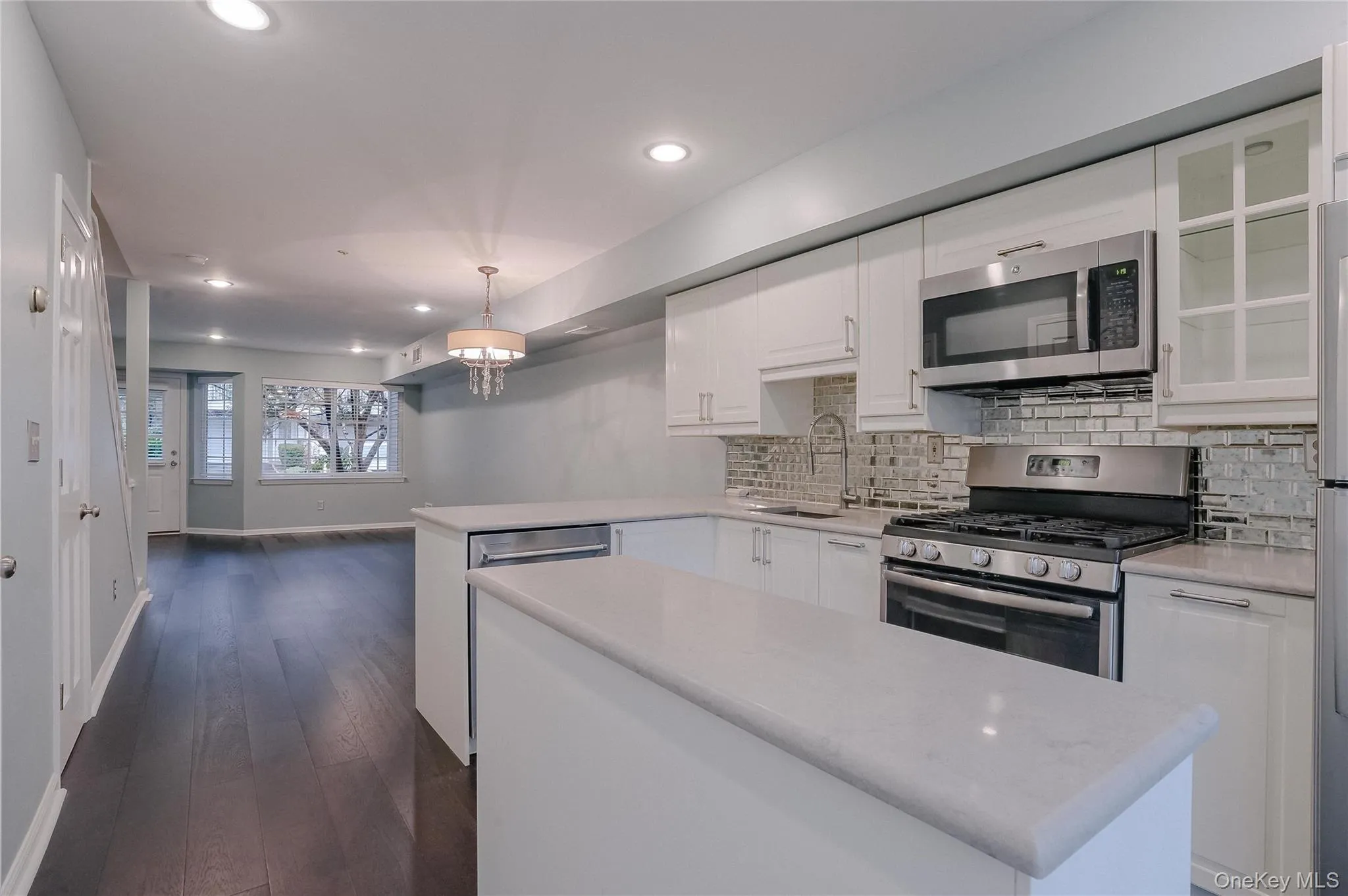 Kitchen with white cabinets, stainless steel appliances, hanging light fixtures, a peninsula, and recessed lighting Kitchen with white cabinets, stainless steel appliances, hanging light fixtures, a peninsula, and recessed lighting