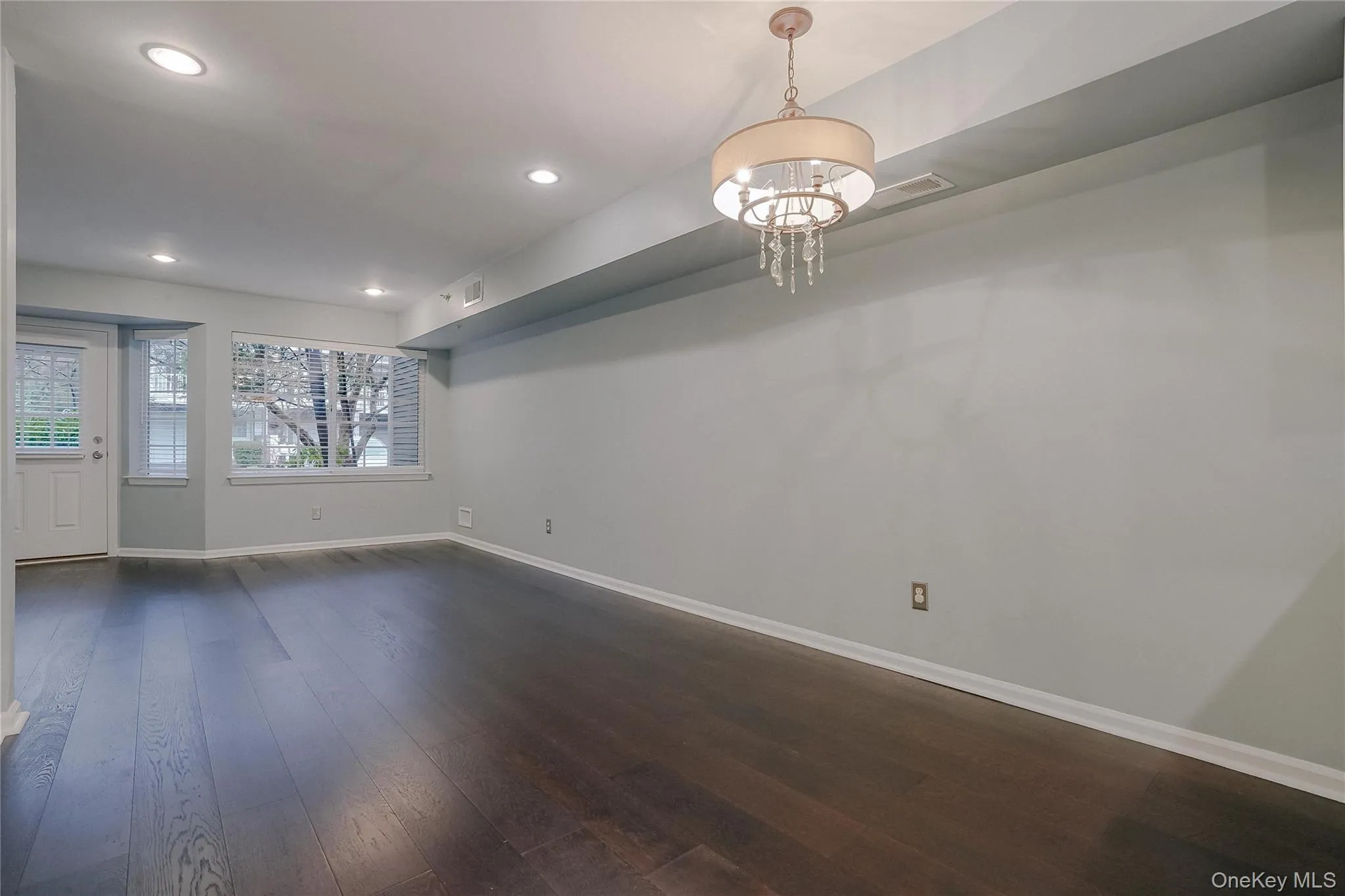 Empty room featuring dark wood-type flooring, recessed lighting, and a chandelier Empty room featuring dark wood-type flooring, recessed lighting, and a chandelier