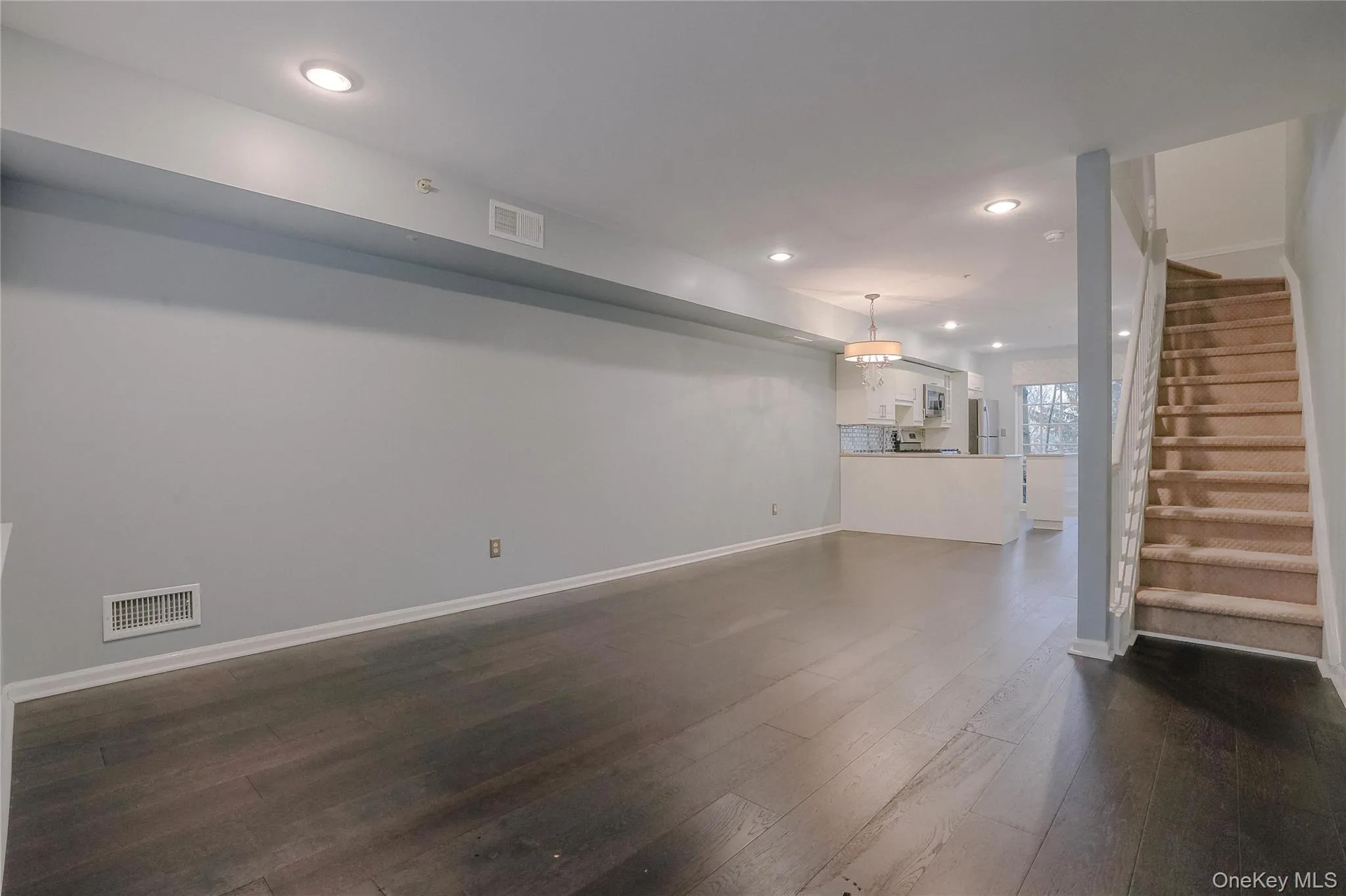 Unfurnished living room featuring recessed lighting, stairway, and dark wood-style flooring Unfurnished living room featuring recessed lighting, stairway, and dark wood-style flooring