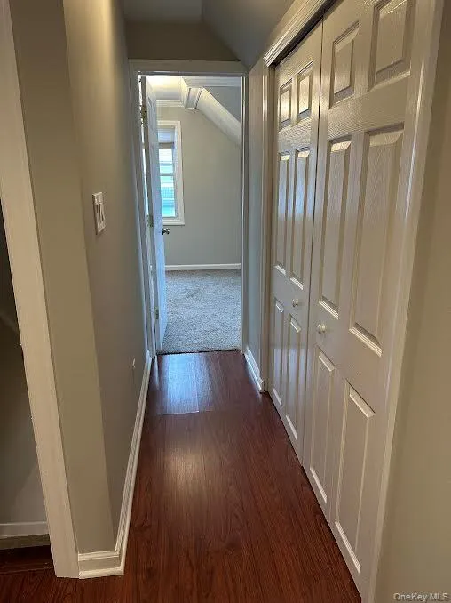 Hallway with vaulted ceiling and dark wood-style flooring Hallway with vaulted ceiling and dark wood-style flooring
