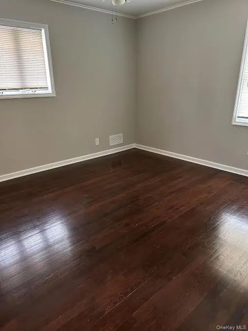 Spare room featuring crown molding and dark wood-type flooring Spare room featuring crown molding and dark wood-type flooring