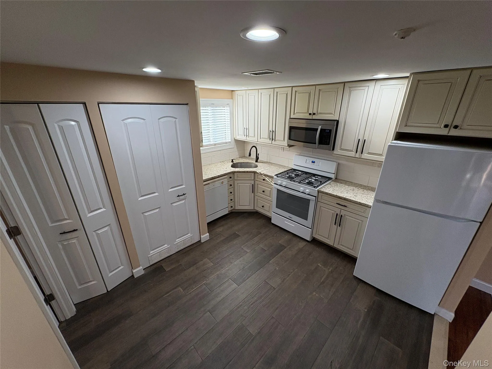 Kitchen with white appliances, dark wood-type flooring, and recessed lighting Kitchen with white appliances, dark wood-type flooring, and recessed lighting