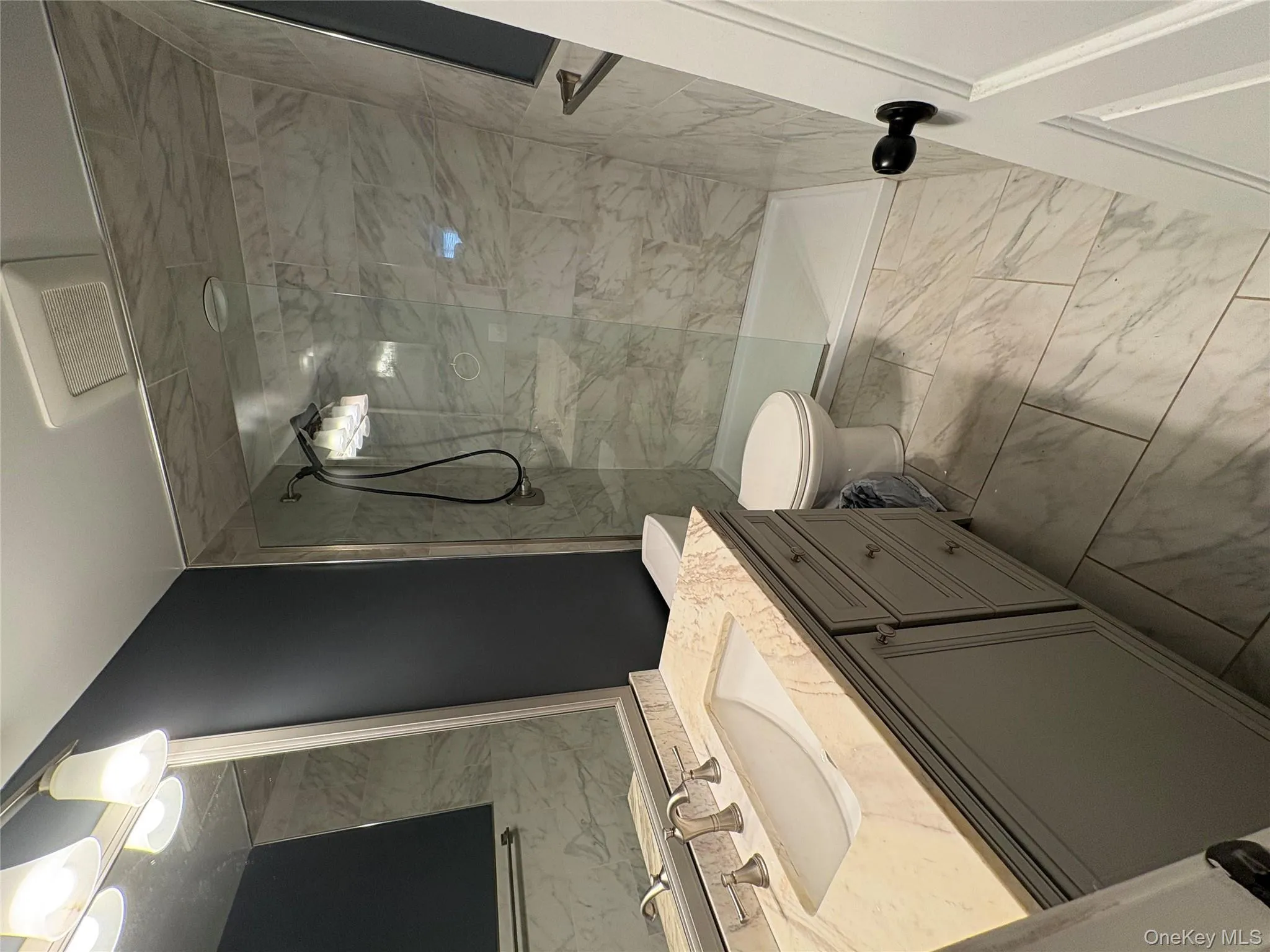 Full bath with light marble finish floors, a marble finish shower, and vanity Full bath with light marble finish floors, a marble finish shower, and vanity