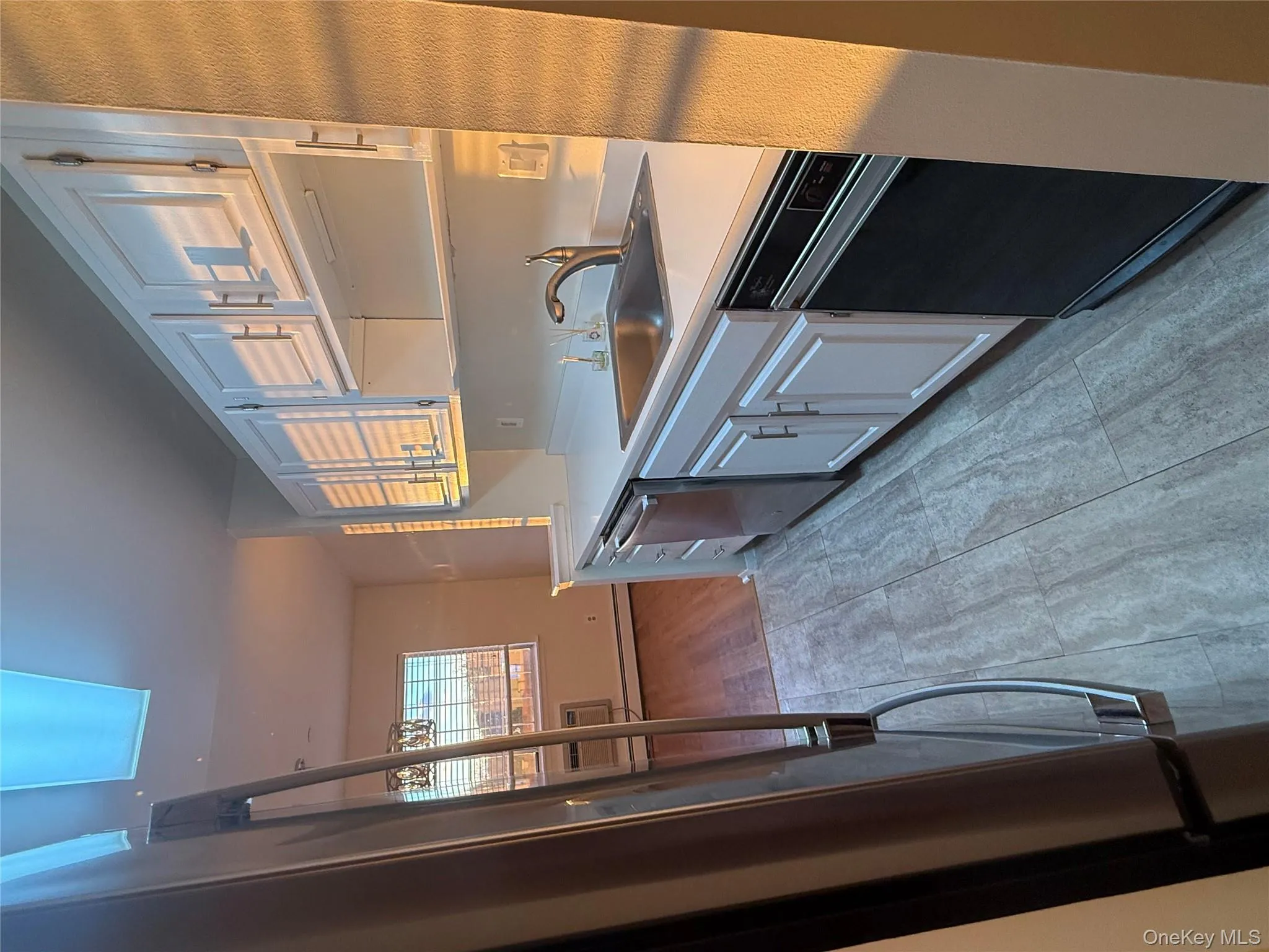 Kitchen featuring light countertops, fridge, dishwashing machine, and white cabinetry Kitchen featuring light countertops, fridge, dishwashing machine, and white cabinetry