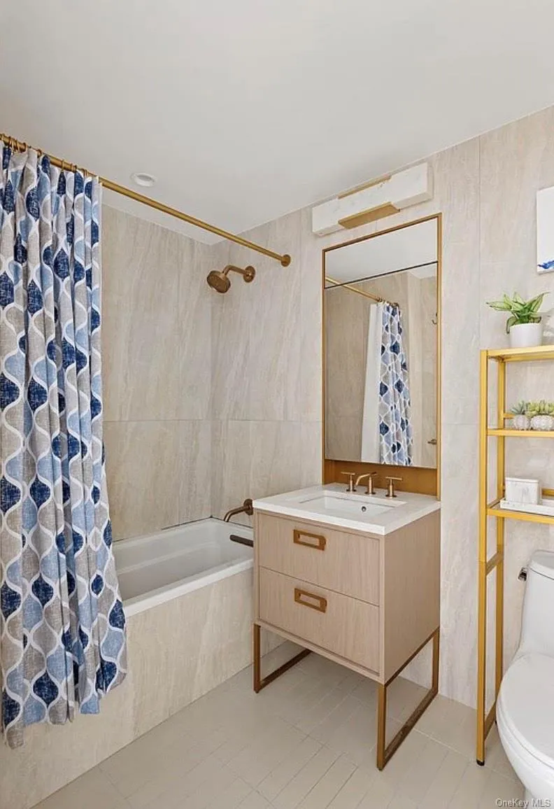 Full bathroom with tile walls, tiled shower / bath, vanity, and light tile patterned floors Full bathroom with tile walls, tiled shower / bath, vanity, and light tile patterned floors