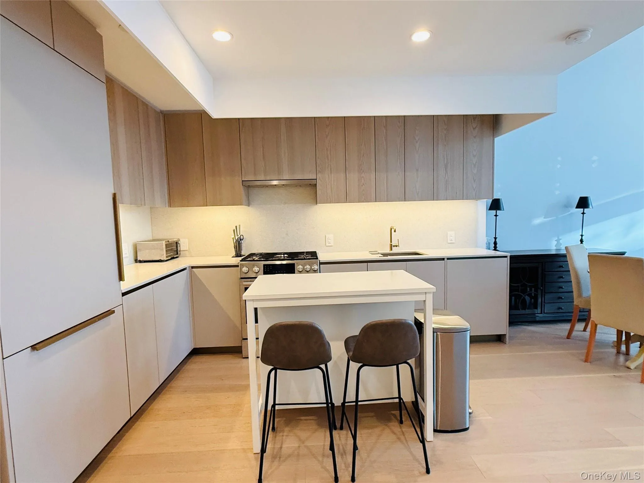 Kitchen featuring a kitchen bar, modern cabinets, stainless steel gas range oven, a kitchen island, and recessed lighting Kitchen featuring a kitchen bar, modern cabinets, stainless steel gas range oven, a kitchen island, and recessed lighting