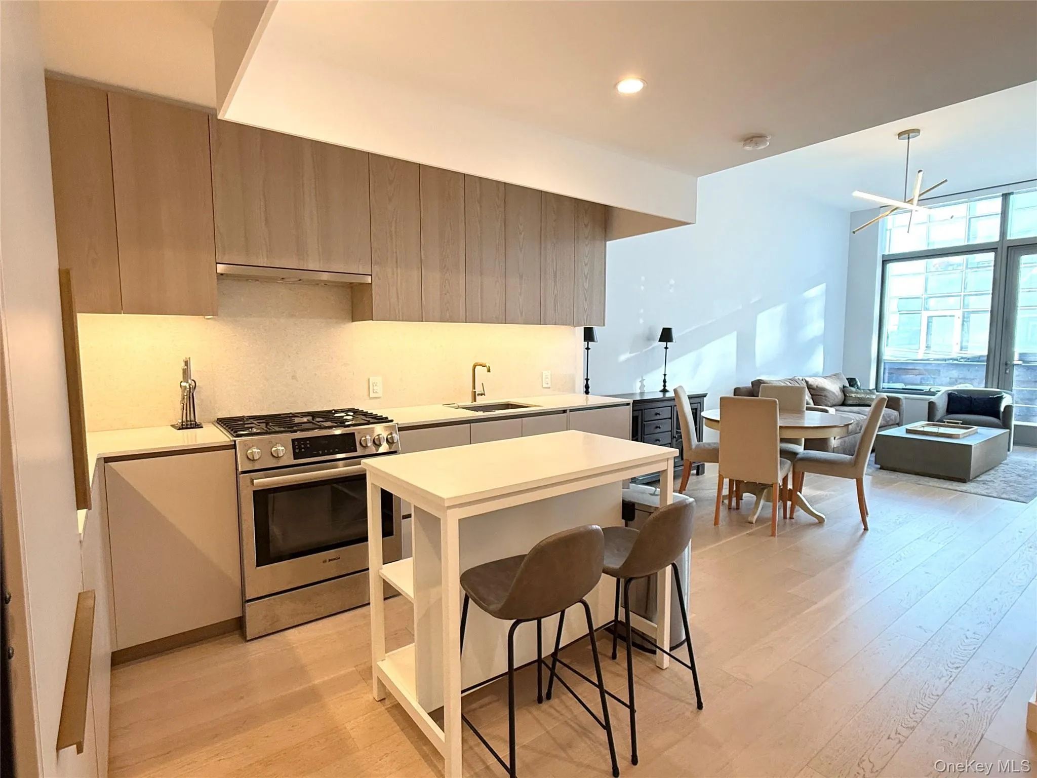 Kitchen featuring light countertops, stainless steel range with gas stovetop, modern cabinets, and a wall of windows Kitchen featuring light countertops, stainless steel range with gas stovetop, modern cabinets, and a wall of windows