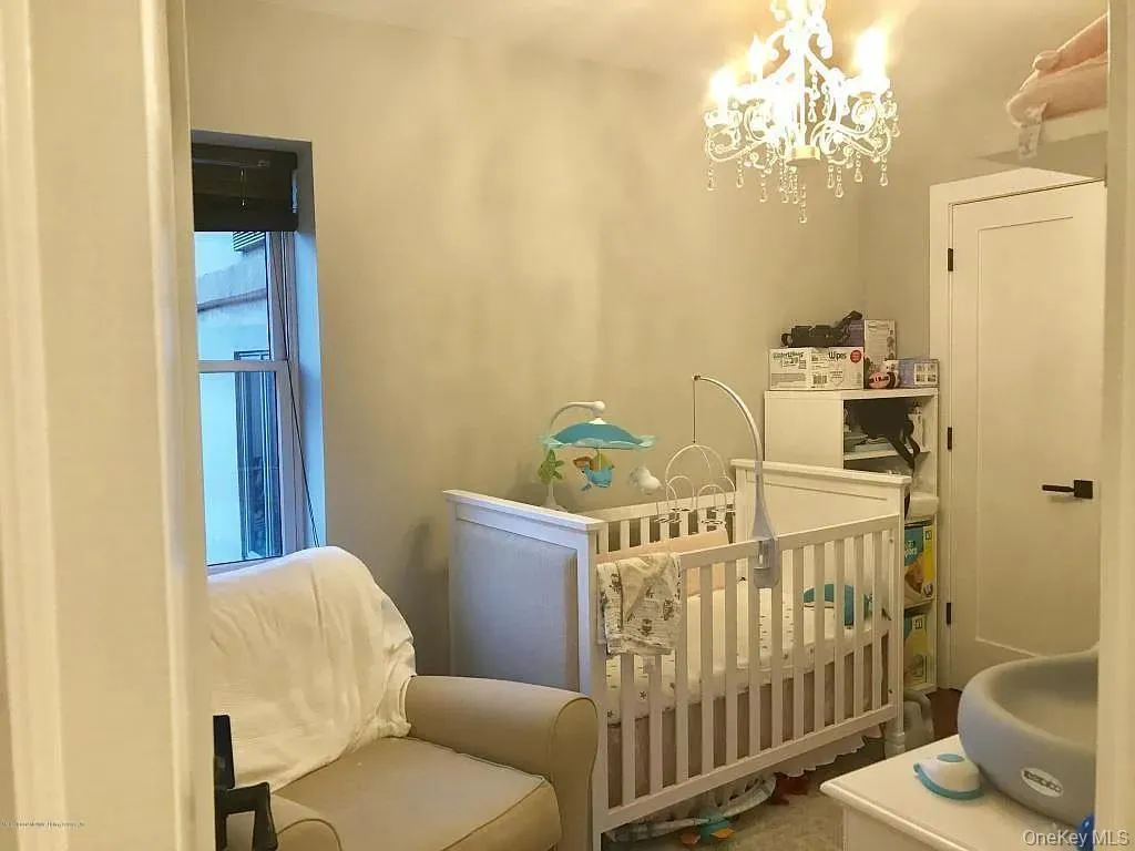Bedroom featuring a crib and a chandelier Bedroom featuring a crib and a chandelier