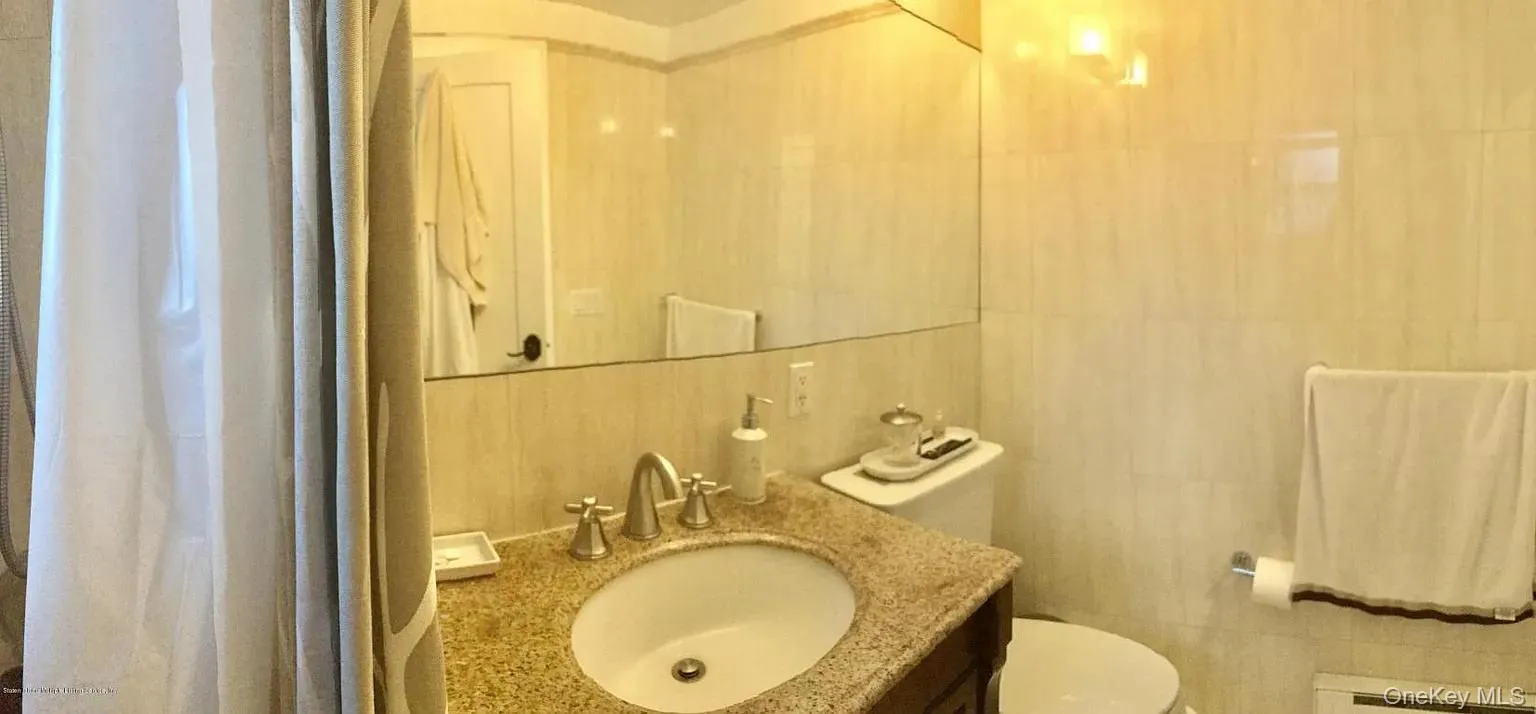 Bathroom with tile walls, vanity, and a baseboard heating unit Bathroom with tile walls, vanity, and a baseboard heating unit