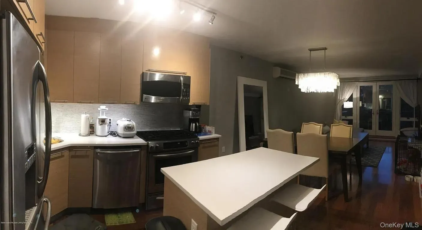 Kitchen featuring appliances with stainless steel finishes, light countertops, tasteful backsplash, decorative light fixtures, and modern cabinets Kitchen featuring appliances with stainless steel finishes, light countertops, tasteful backsplash, decorative light fixtures, and modern cabinets