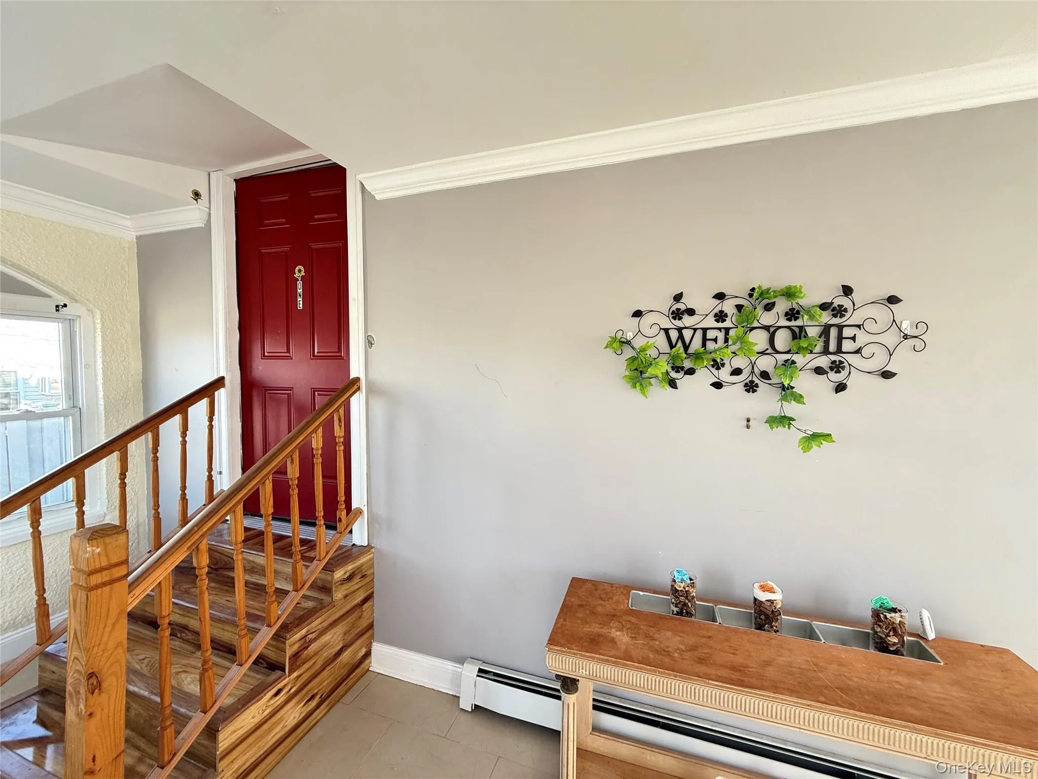 Stairs featuring crown molding, a baseboard heating unit, and tile patterned flooring Stairs featuring crown molding, a baseboard heating unit, and tile patterned flooring