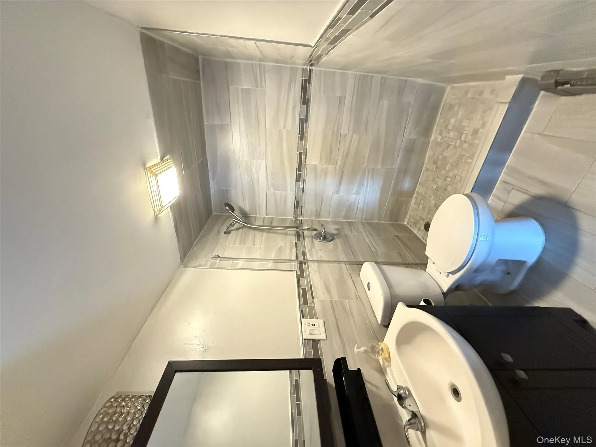 Bathroom featuring a stall shower, vanity, tile walls, and wainscoting Bathroom featuring a stall shower, vanity, tile walls, and wainscoting