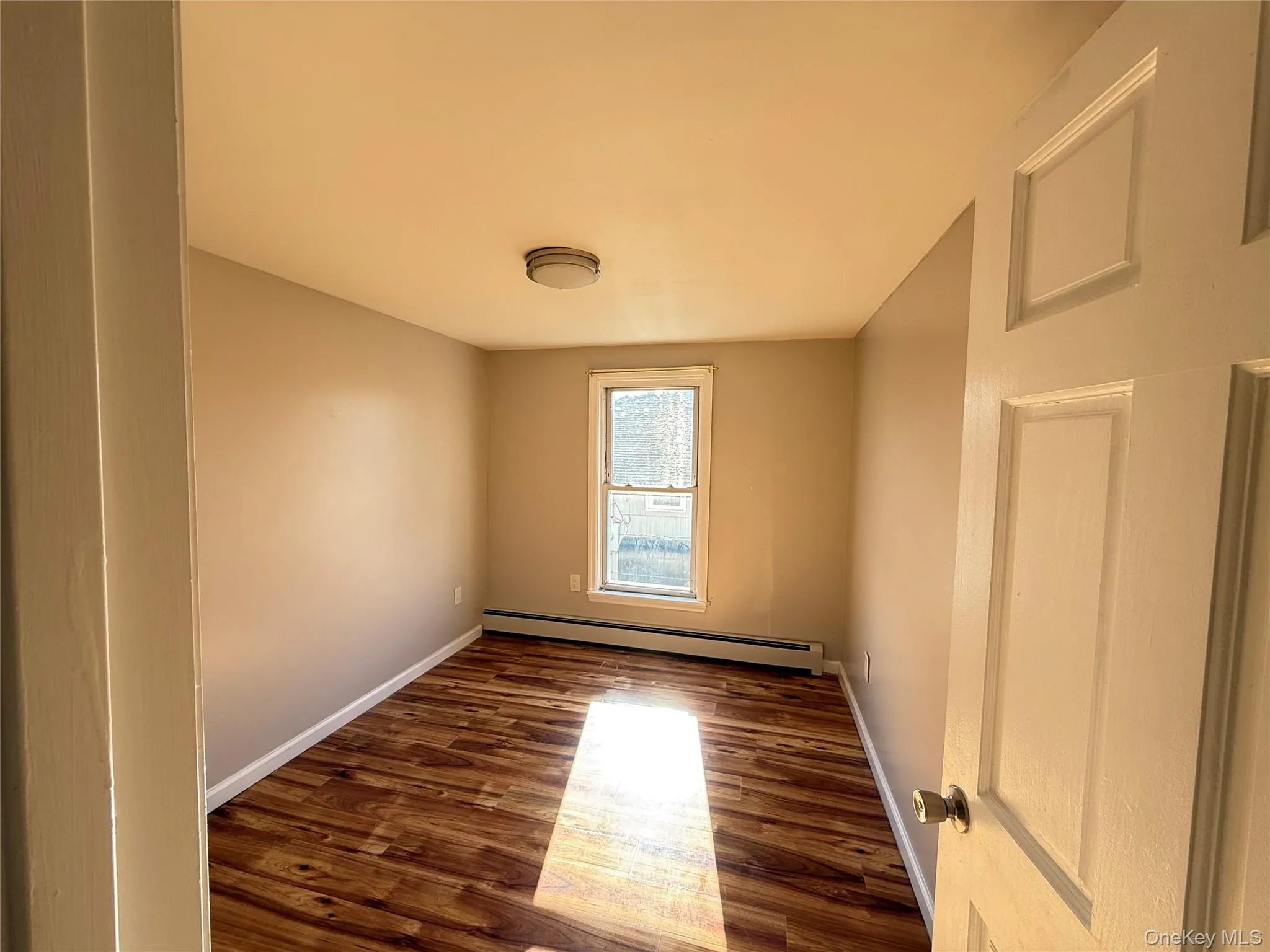 Empty room with a baseboard radiator and dark wood finished floors Empty room with a baseboard radiator and dark wood finished floors