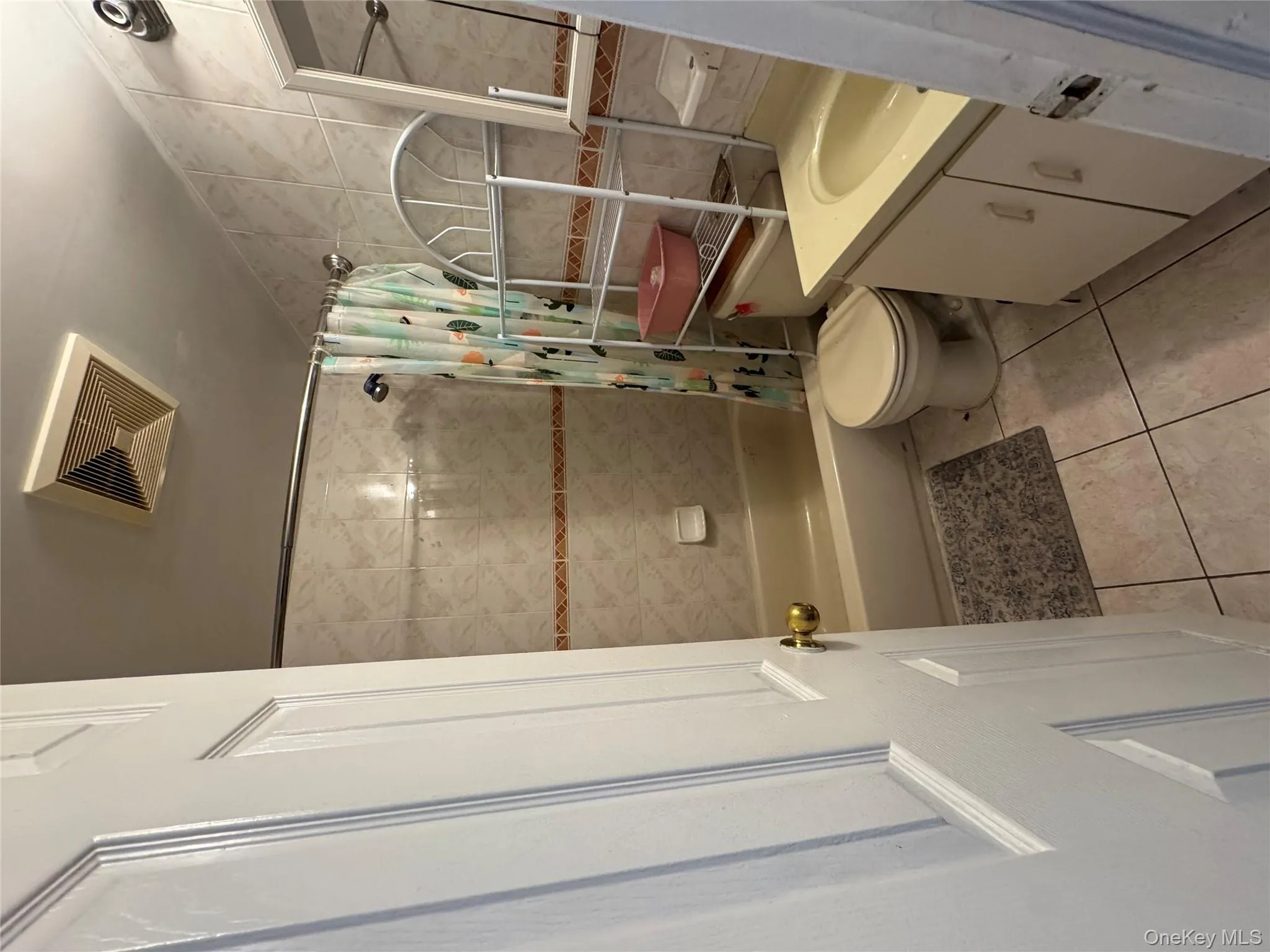 Full bath with tile walls, vanity, shower / bath combination with curtain, and light tile patterned flooring Full bath with tile walls, vanity, shower / bath combination with curtain, and light tile patterned flooring