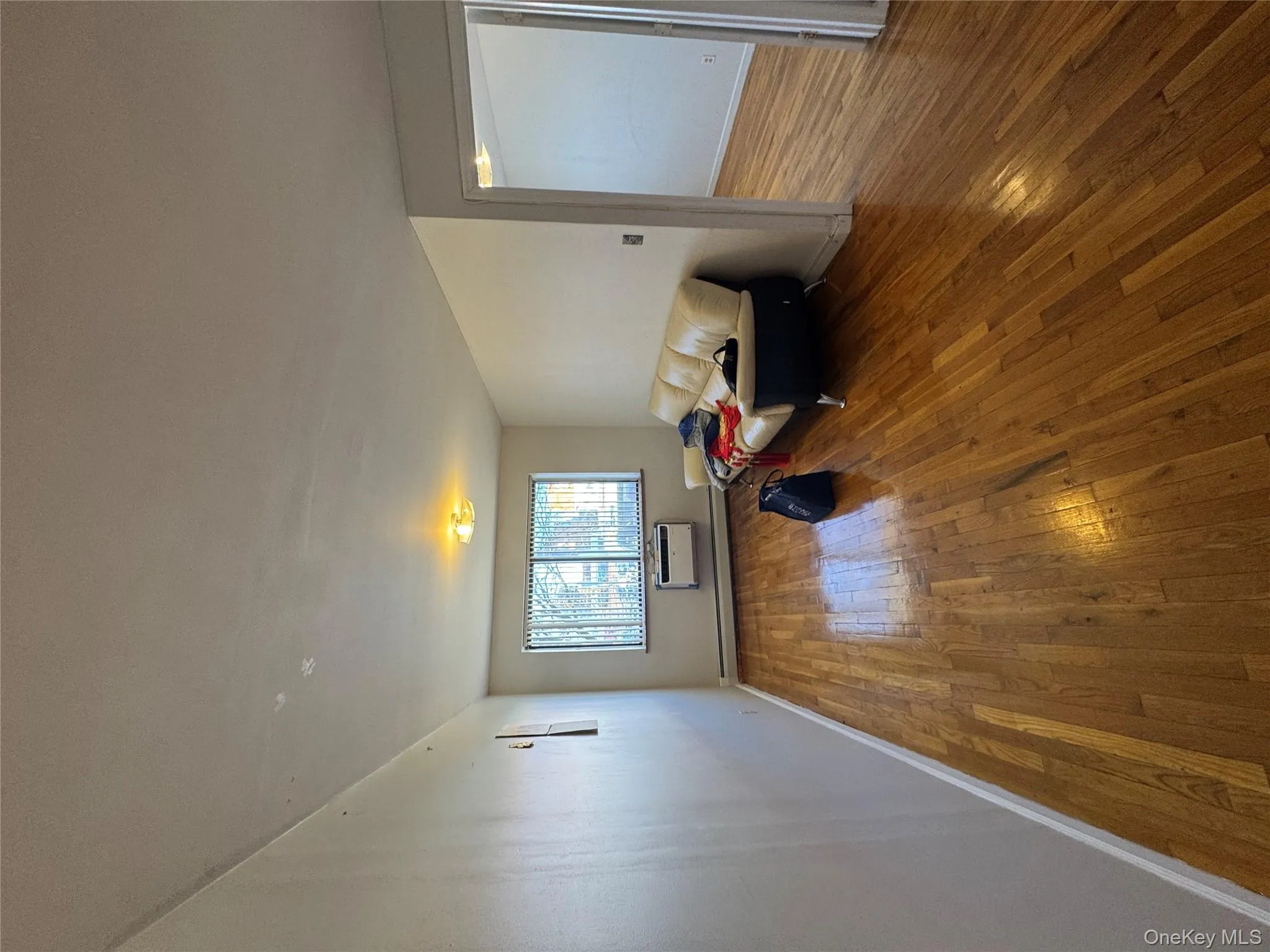 Living area with an AC wall unit, hardwood / wood-style floors, and baseboard heating Living area with an AC wall unit, hardwood / wood-style floors, and baseboard heating