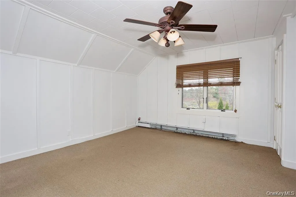 Additional living space featuring a decorative wall, a baseboard radiator, a ceiling fan, light colored carpet, and lofted ceiling Additional living space featuring a decorative wall, a baseboard radiator, a ceiling fan, light colored carpet, and lofted ceiling
