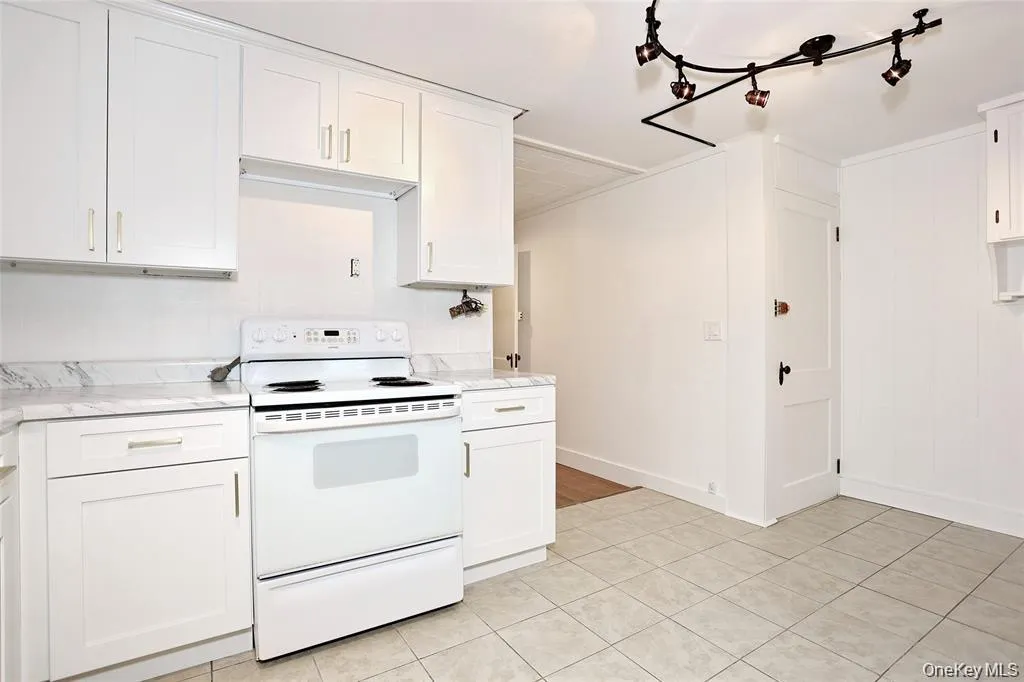 Kitchen featuring electric stove, white cabinets, and light tile patterned floors Kitchen featuring electric stove, white cabinets, and light tile patterned floors