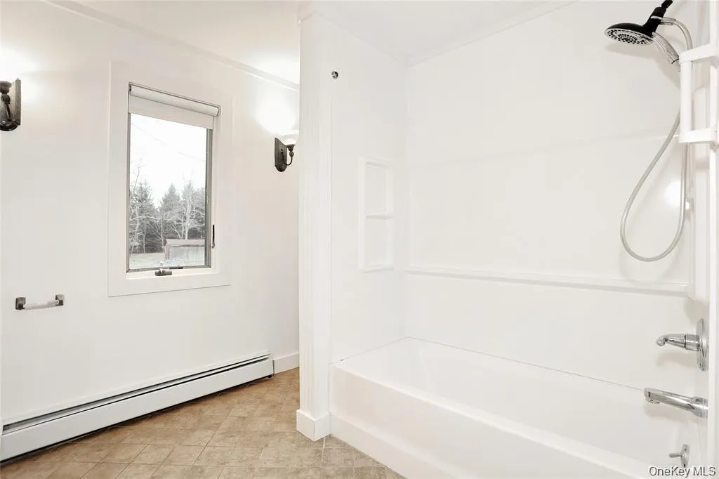 Bathroom featuring a baseboard heating unit and bathtub / shower combination Bathroom featuring a baseboard heating unit and bathtub / shower combination