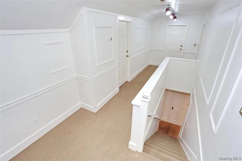 Hall featuring an upstairs landing and light carpet Hall featuring an upstairs landing and light carpet