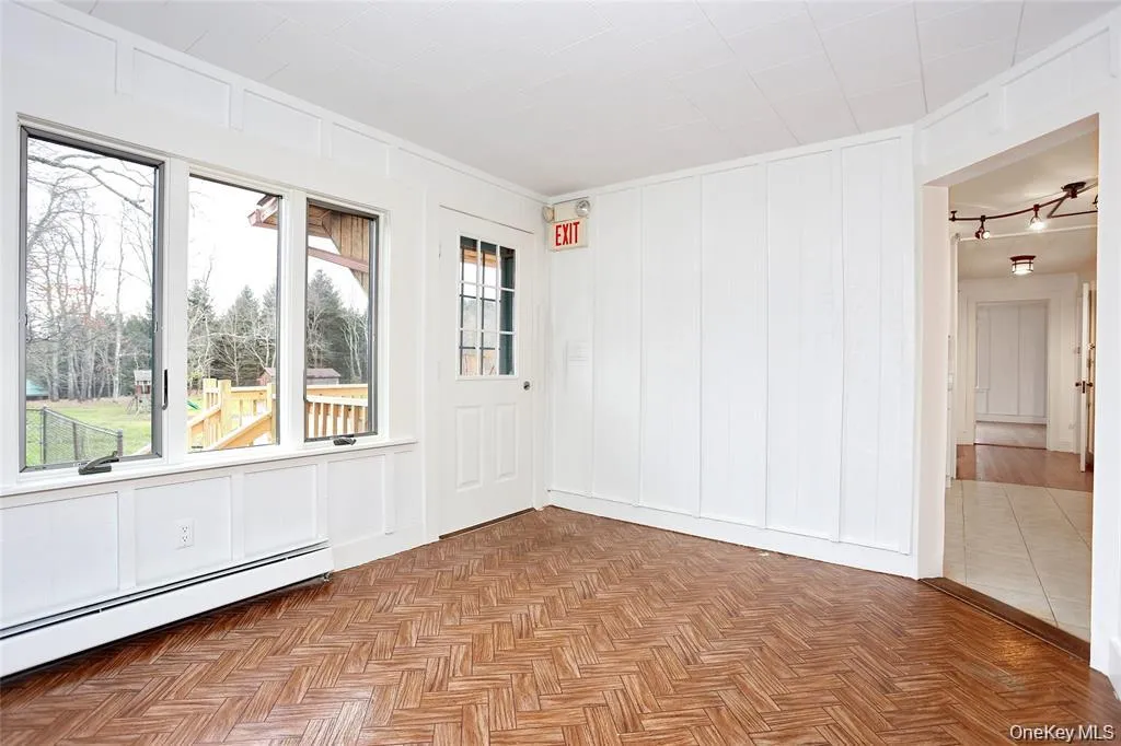 Unfurnished room featuring a decorative wall and baseboard heating Unfurnished room featuring a decorative wall and baseboard heating