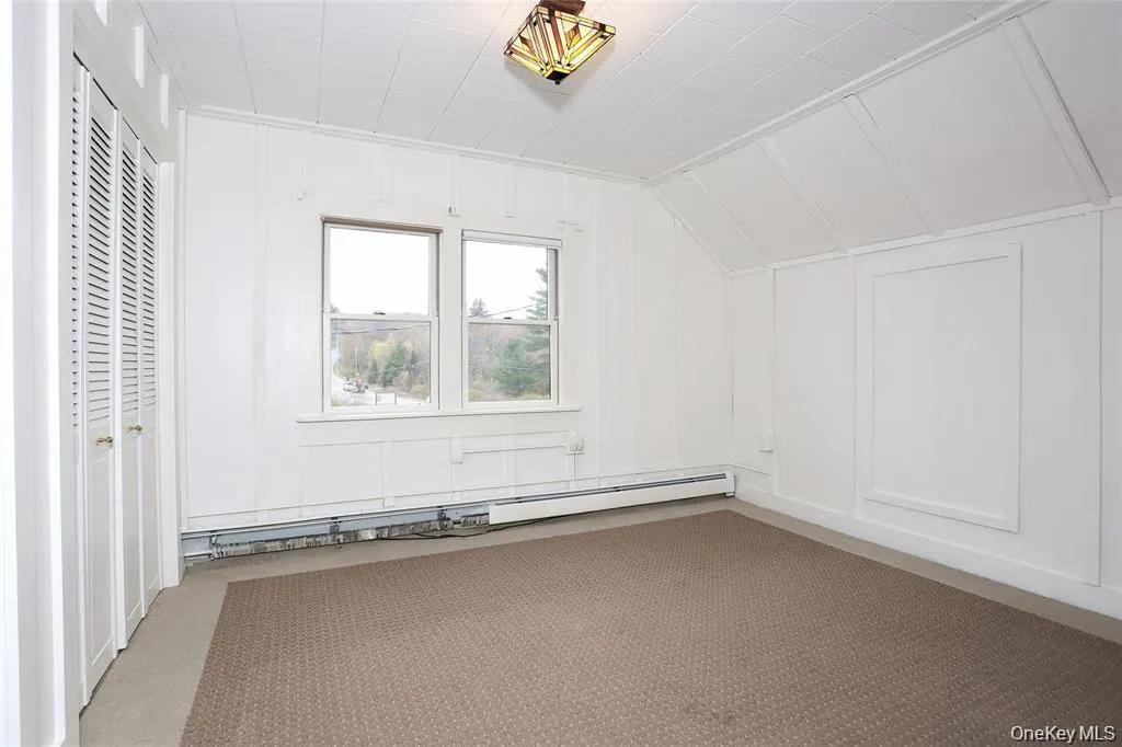 Additional living space featuring a decorative wall, carpet flooring, a baseboard heating unit, and lofted ceiling Additional living space featuring a decorative wall, carpet flooring, a baseboard heating unit, and lofted ceiling