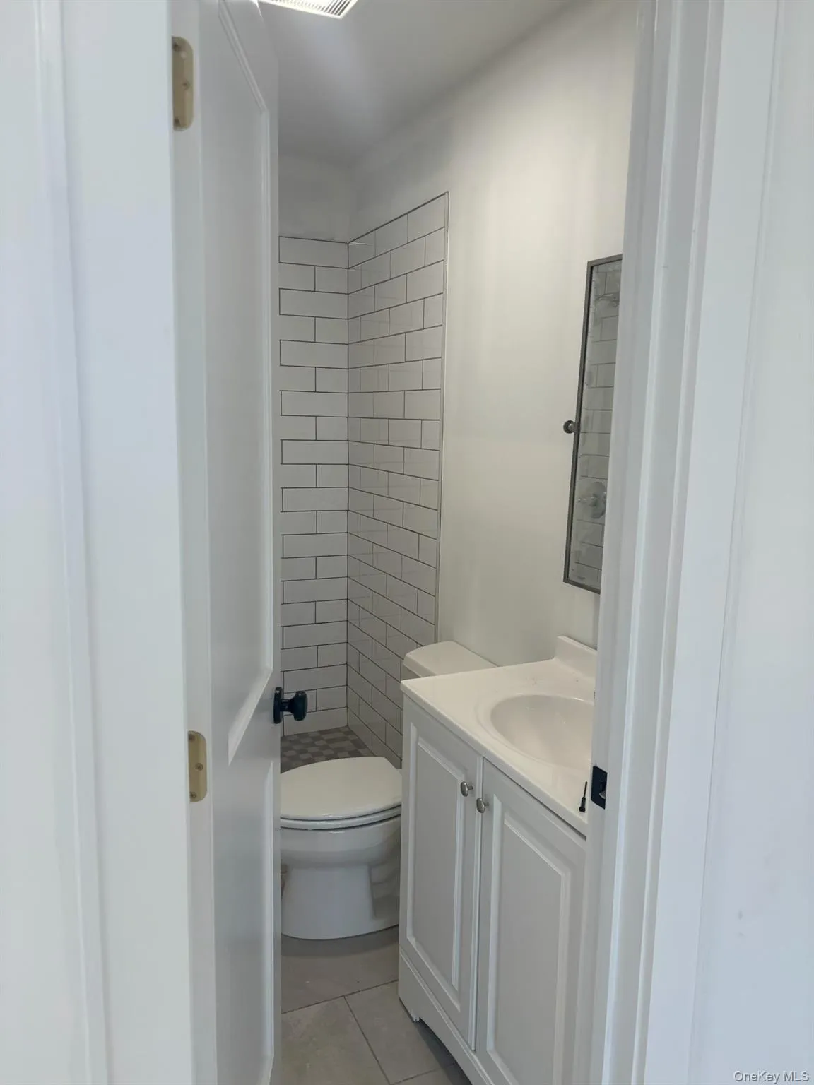 Bathroom with vanity, light tile patterned flooring, and a tile shower Bathroom with vanity, light tile patterned flooring, and a tile shower