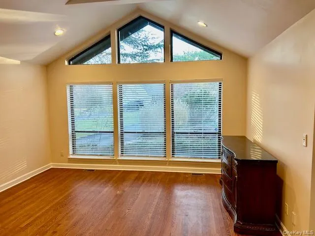 Empty room with healthy amount of natural light, dark wood finished floors, and lofted ceiling Empty room with healthy amount of natural light, dark wood finished floors, and lofted ceiling