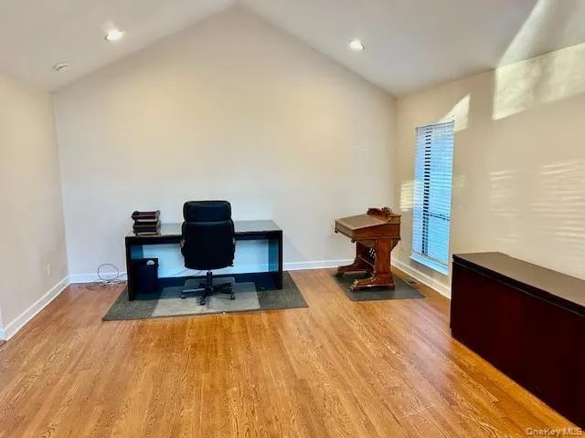 Office space featuring wood finished floors, vaulted ceiling, and recessed lighting Office space featuring wood finished floors, vaulted ceiling, and recessed lighting