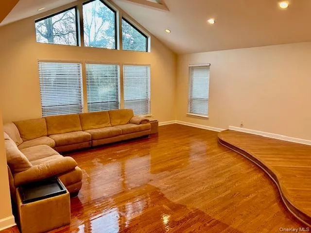 Living area with light wood-style floors, high vaulted ceiling, and recessed lighting Living area with light wood-style floors, high vaulted ceiling, and recessed lighting
