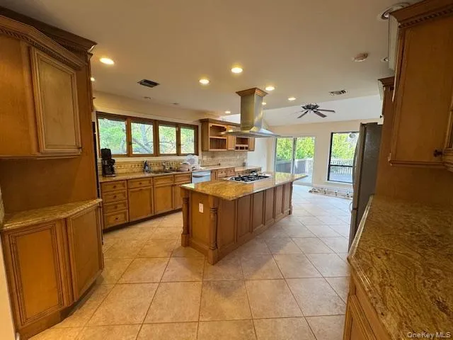Kitchen featuring brown cabinetry, recessed lighting, healthy amount of natural light, backsplash, and light stone counters Kitchen featuring brown cabinetry, recessed lighting, healthy amount of natural light, backsplash, and light stone counters