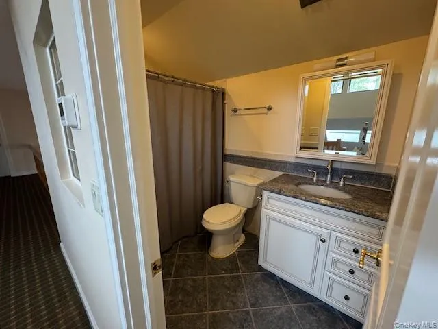 Full bathroom with a shower with curtain, vanity, and dark tile patterned flooring Full bathroom with a shower with curtain, vanity, and dark tile patterned flooring