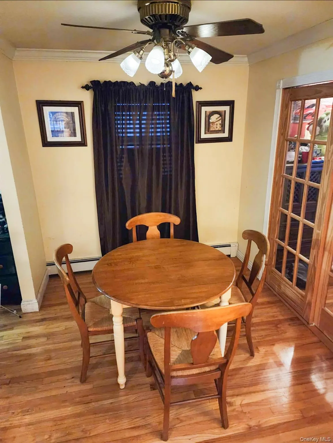 Dining area with crown molding, ceiling fan, light wood-style floors, and a baseboard heating unit Dining area with crown molding, ceiling fan, light wood-style floors, and a baseboard heating unit