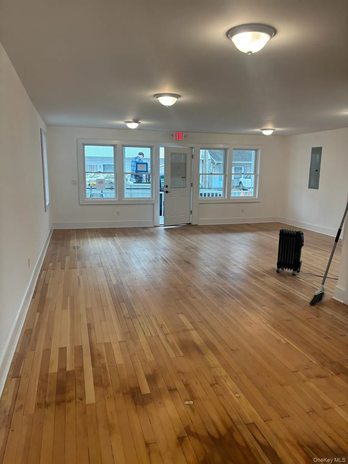 Unfurnished living room featuring plenty of natural light, light wood-type flooring, and electric panel Unfurnished living room featuring plenty of natural light, light wood-type flooring, and electric panel