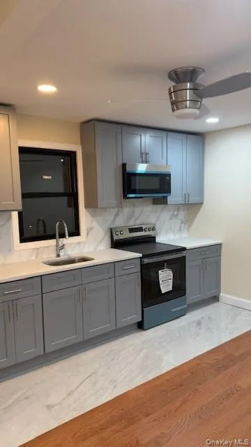 Kitchen featuring gray cabinetry, range with electric cooktop, stainless steel microwave, tasteful backsplash, and recessed lighting Kitchen featuring gray cabinetry, range with electric cooktop, stainless steel microwave, tasteful backsplash, and recessed lighting