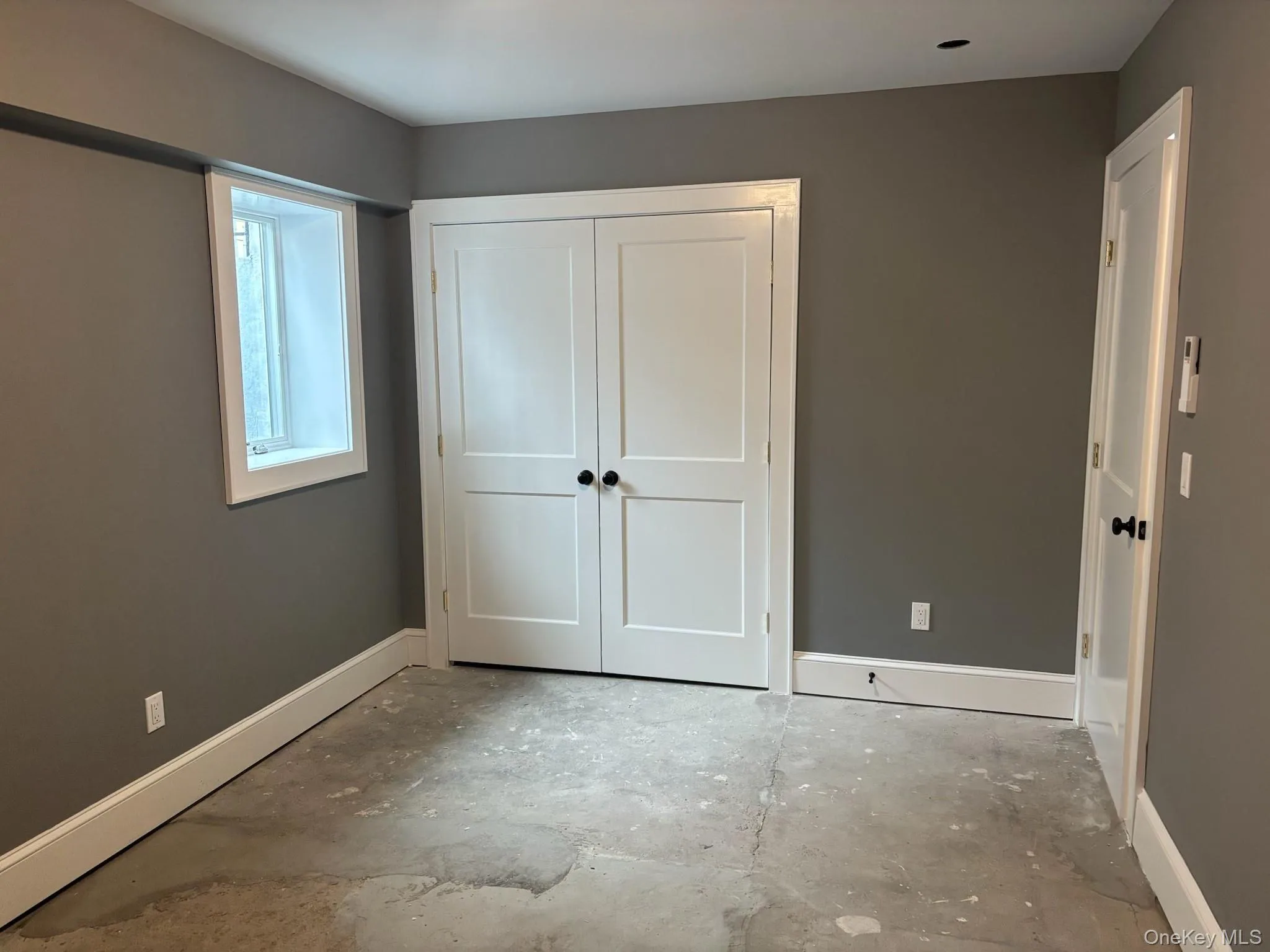 Unfurnished bedroom with a closet and unfinished concrete flooring Unfurnished bedroom with a closet and unfinished concrete flooring