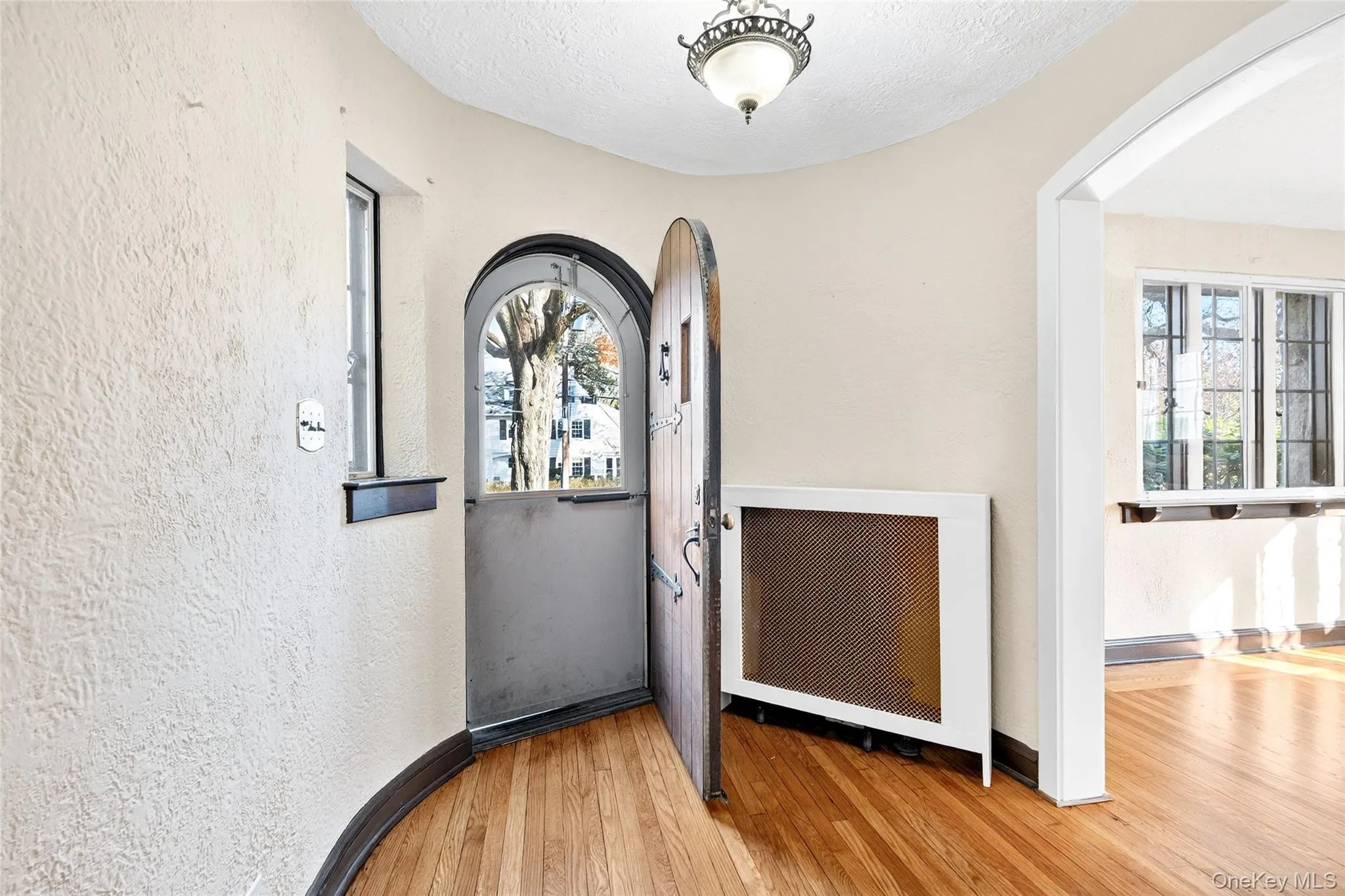 Foyer with arched walkways, light wood finished floors, and a textured wall Foyer with arched walkways, light wood finished floors, and a textured wall