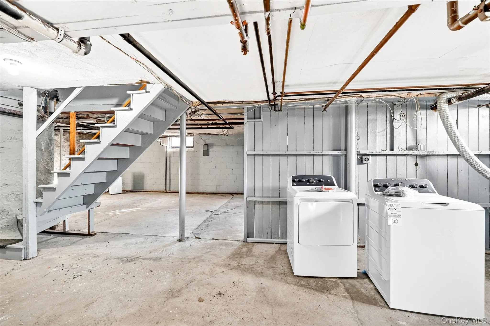 Unfinished below grade area with stairs and washer and dryer Unfinished below grade area with stairs and washer and dryer