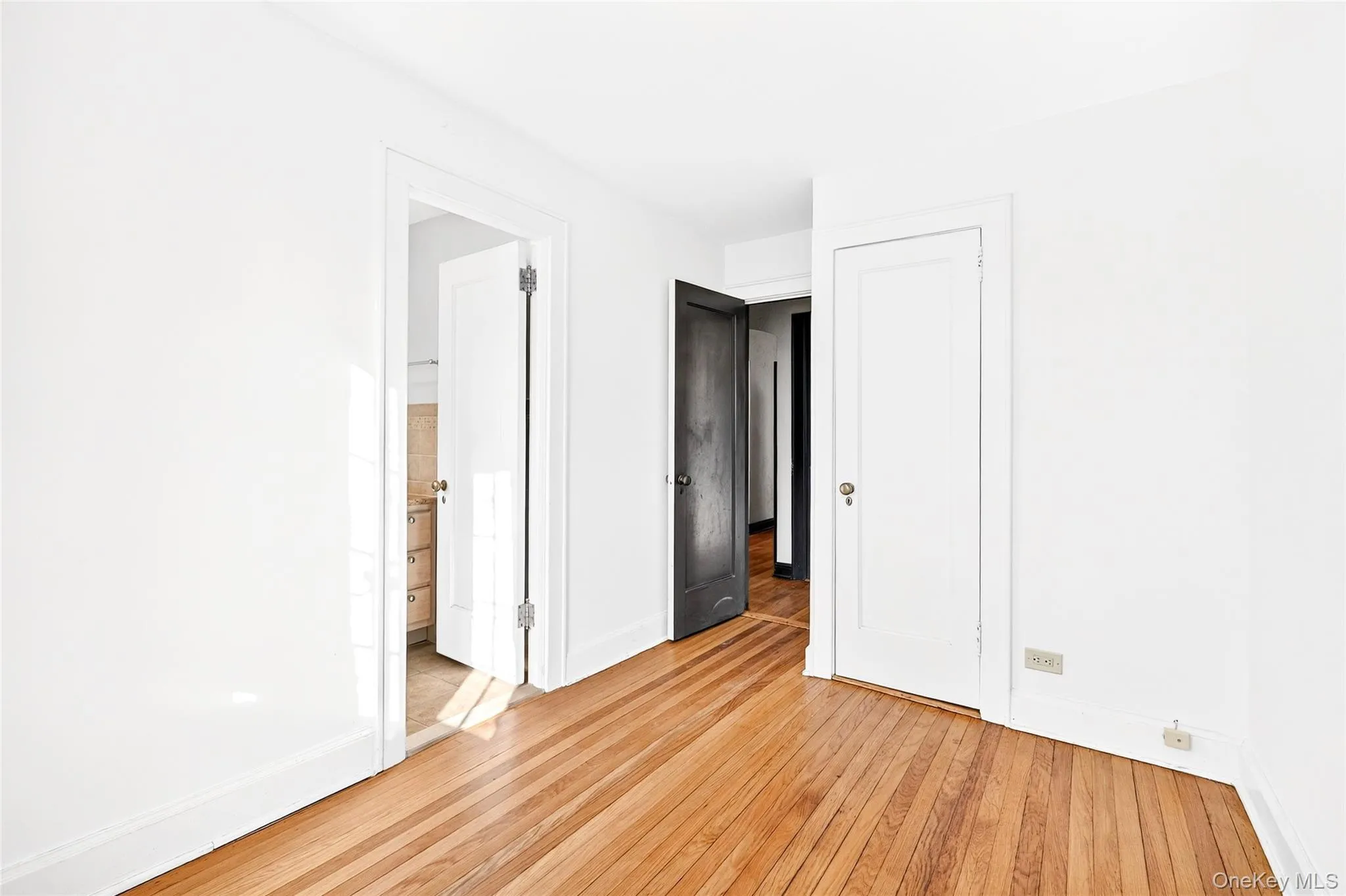 Unfurnished bedroom with light wood-style flooring and ensuite bath Unfurnished bedroom with light wood-style flooring and ensuite bath